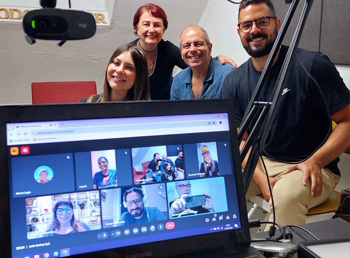 Turma comemorando ao redor do laptop com a transmissão ao vivo em andamento